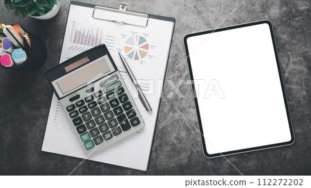 Tablet with charts and reports on office desk workplace. Top view flat lay Tablet with charts and reports on office desk workplace. Top view flat lay 112272202