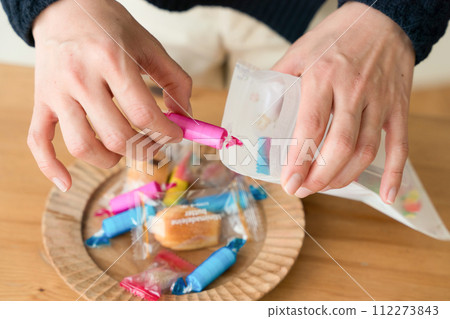 A woman's hand putting sweets into a bag 112273843