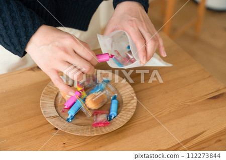 A woman's hand putting sweets into a bag 112273844