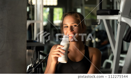 Healthy lifestyle woman drink milk at fitness gym. Young people girl workout exercise  112275544