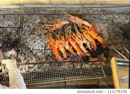 Ama divers grilling fresh spiny lobster over charcoal at an ama hut, Mie Prefecture, Japan 112276146