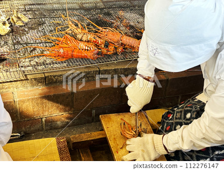 An ama diver cuts charcoal-grilled spiny lobster with a knife, Mie Prefecture, Japan An ama diver cuts charcoal-grilled spiny lobster with a knife, Mie Prefecture, Japan 112276147