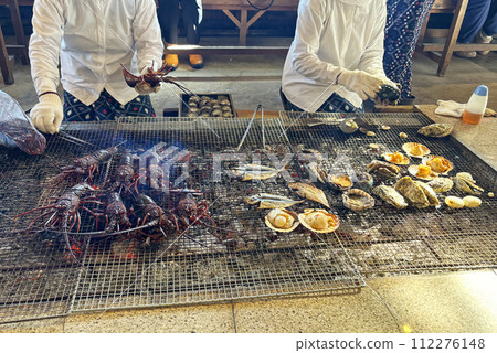 Ama divers grilling fresh lobster, shellfish, and fish over charcoal at an ama hut, Mie Prefecture, Japan 112276148