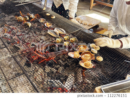 Ama divers grilling fresh lobster, shellfish, and fish over charcoal at the ama hut, Mie Prefecture, Japan 112276151