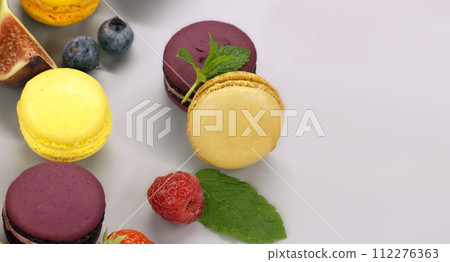Vibrant scene of table filled with macaroons and fruits 112276363