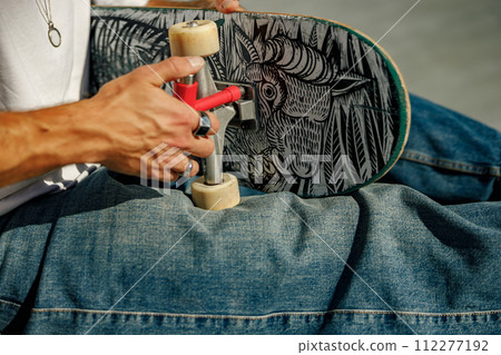 View of a man repairing his skateboard in the skate park. Extreme sport concept 112277192