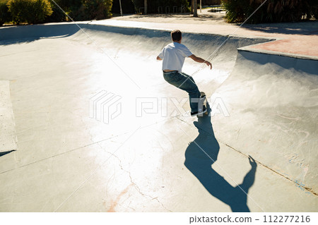 Active young man riding skateboard in skate park on sunny day. Extreme sport concept 112277216