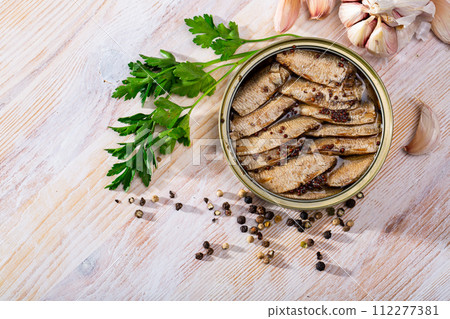 Tinned small smoked sardines on background with greens 112277381