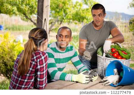 Farmers talking while sitting at table in the garden Farmers talking while sitting at table in the garden 112277479