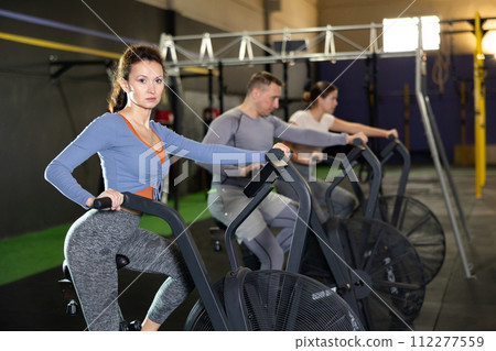 Focused woman doing cardio training on air bike in gym Focused woman doing cardio training on air bike in gym 112277559
