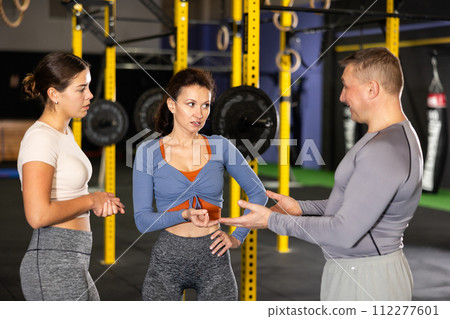 Man and two women talking in gym 112277601
