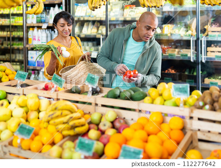 Hispanic couple choosing vegetables and fruits in grocery store 112277642