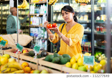 Female looking for tomatoes in greengrocery department of supermarket Female looking for tomatoes in greengrocery department of supermarket 112277649