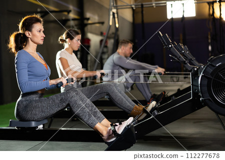 Concentrated woman working out on rowing machine in gym 112277678