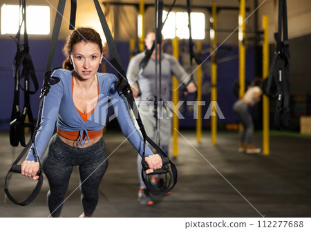Female athlete with group working out on gymnastics rings at crossfit gym Female athlete with group working out on gymnastics rings at crossfit gym 112277688