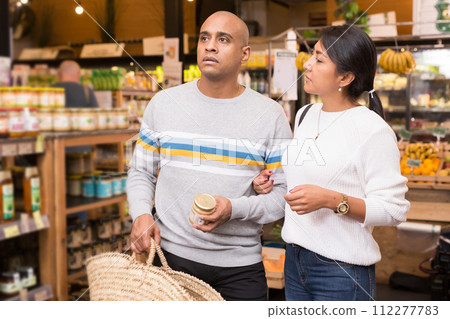 Happy hispanic couple choosing foods in grocery shop Happy hispanic couple choosing foods in grocery shop 112277783