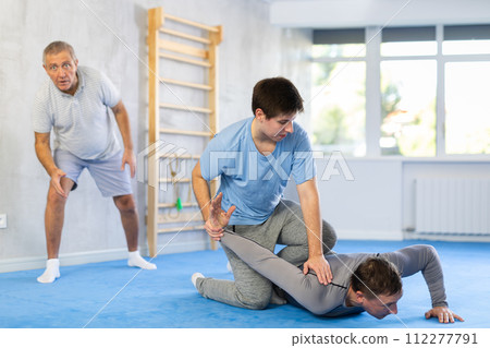 Adult and young men training self-defense techniques Adult and young men training self-defense techniques 112277791