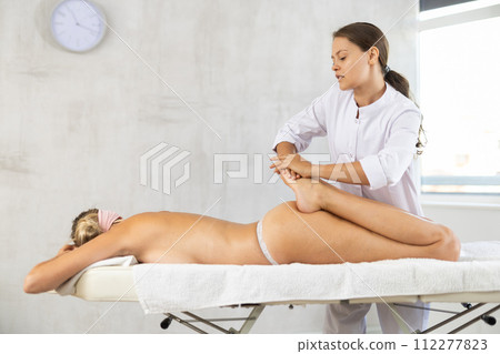 During massage, doctor works out legs shins kneads and stretches and increases mobility in joints 112277823