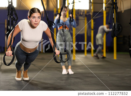 Active athlete young woman during exercises on crossover exercise machine with loops and weighting Active athlete young woman during exercises on crossover exercise machine with loops and weighting 112277832