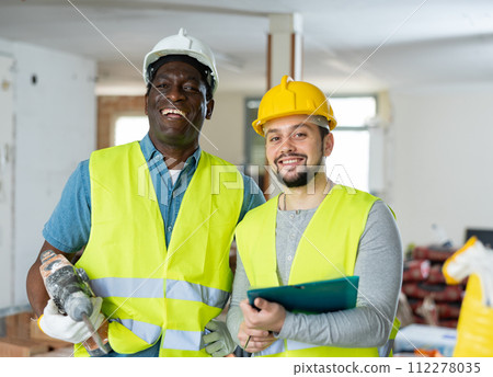 Two builders talking on indoor construction site Two builders talking on indoor construction site 112278035