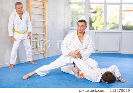 Focused adult jiu-jitsu fighter performing painful armlock during sparring Focused adult jiu-jitsu fighter performing painful armlock during sparring 112278059
