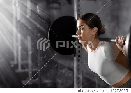 Caucasian woman training with barbell using squat rack in crossfit gym Caucasian woman training with barbell using squat rack in crossfit gym 112278095