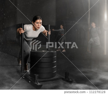 Young woman during grueling workout with element of push and pull superset in fitness club 112278128