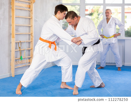 Experienced karate instructor demonstrating techniques in sparring with young fighter 112278250
