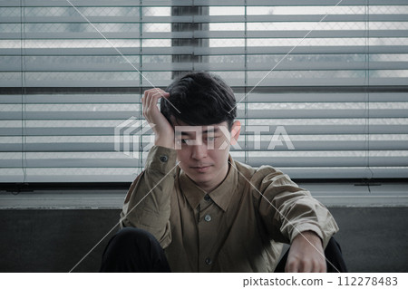 Young man depressed in a dark room 112278483