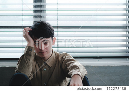 Young man depressed in a dark room Young man depressed in a dark room 112278486