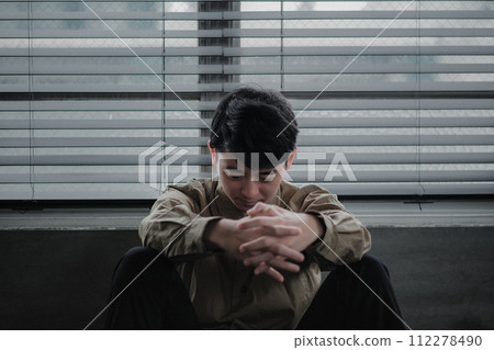 Young man depressed in a dark room 112278490