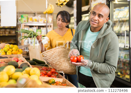 Married couple choosing tomatoes at grocery store Married couple choosing tomatoes at grocery store 112278496