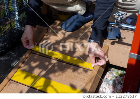 A man attaching anti-slip to a wooden deck sloop A man attaching anti-slip to a wooden deck sloop 112278537