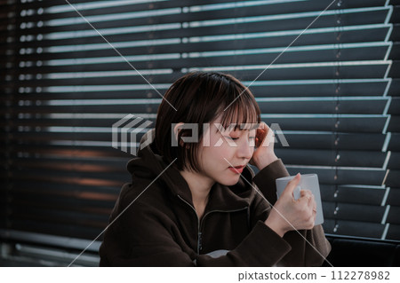 一位穿著家居服的女士坐在沙發上看著智慧型手機 112278982