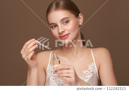 Woman holding a cosmetic jar of oil serum Woman holding a cosmetic jar of oil serum 112282521