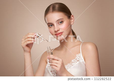 Woman holding a cosmetic jar of oil serum Woman holding a cosmetic jar of oil serum 112282522