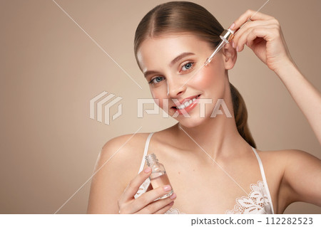 Young beautiful woman applying face serum 112282523