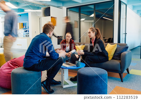 Multiethnic startup business team on meeting in a modern bright open space coworking office. Brainstorming, working on laptop. Group of coworkers walking around in motion blur Multiethnic startup business team on meeting in a modern bright open space coworking office. Brainstorming, working on laptop. Group of coworkers walking around in motion blur 112283519