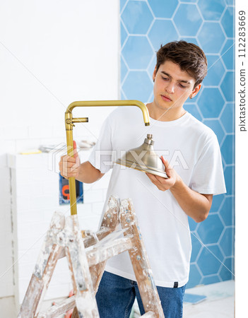 Guy installing shower in bathroom in house under renovation 112283669