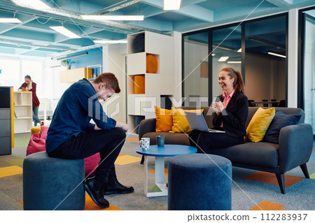 Multiethnic startup business team on meeting in a modern bright open space coworking office. Brainstorming, working on laptop. Group of coworkers walking around in motion blur 112283937