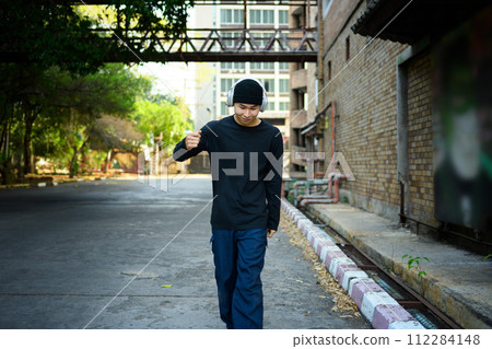 Handsome young man listening to music with headphones walking through the city 112284148