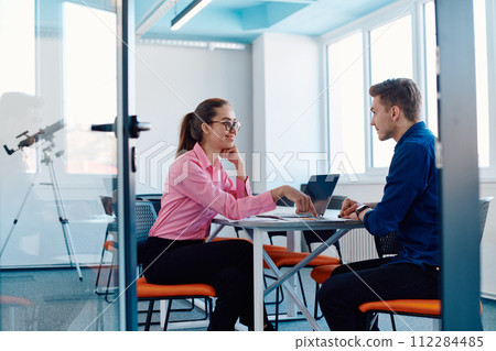 In a sleek, modern glass office, the director engages in a productive discussion with an employee, focusing on business projects and fostering collaboration In a sleek, modern glass office, the director engages in a productive discussion with an employee, focusing on business projects and fostering collaboration 112284485