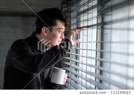 一個男人手裡拿著咖啡杯看著窗外 112284681