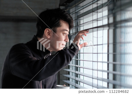 一個男人手裡拿著咖啡杯看著窗外 112284682