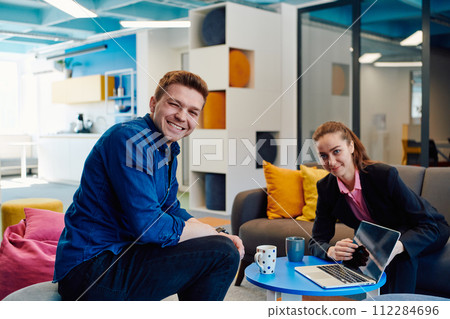 Multiethnic startup business team on meeting in a modern bright open space coworking office. Brainstorming, working on laptop. Group of coworkers walking around in motion blur 112284696