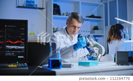 Molecular chemistry lab scientist examining liquid under microscope, research Molecular chemistry lab scientist examining liquid under microscope, research 112284770