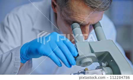 Serious male scientist looking into lab microscope lens, working on research, medicine Serious male scientist looking into lab microscope lens, working on research, medicine 112284786