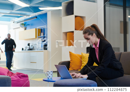 Busy businesswoman using a smartphone. Happy young businesswoman alone in a modern coworking open space office workplace. Business woman connecting with her clients in an office Busy businesswoman using a smartphone. Happy young businesswoman alone in a modern coworking open space office workplace. Business woman connecting with her clients in an office 112284875