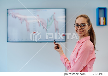 On Stage, Successful Female Speaker Presents Technological Product, Uses Remote Control for Presentation, Showing Infographics, Statistics Animation on Screen. Live Event Device Release 112284916