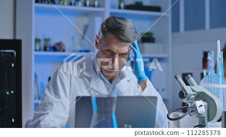 Puzzled medical lab scientist checking virus research progress on computer Puzzled medical lab scientist checking virus research progress on computer 112285378